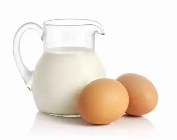 Eine Glaskanne mit Milch und zwei Eier