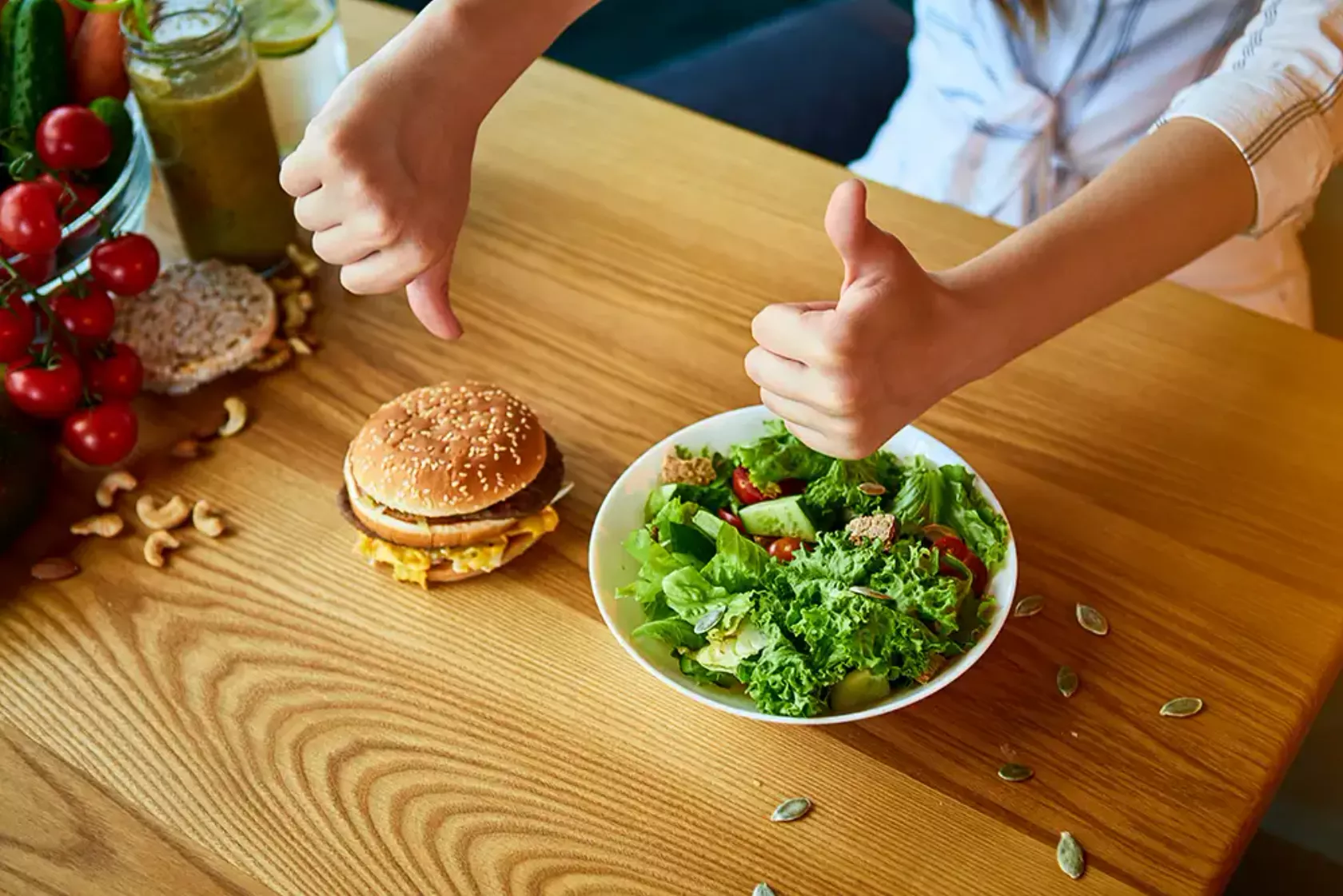 Auf einem Tisch ein Burger und ein Salat und eine Person macht Handzeichen dazu - Daumen runter, Daumen rauf.