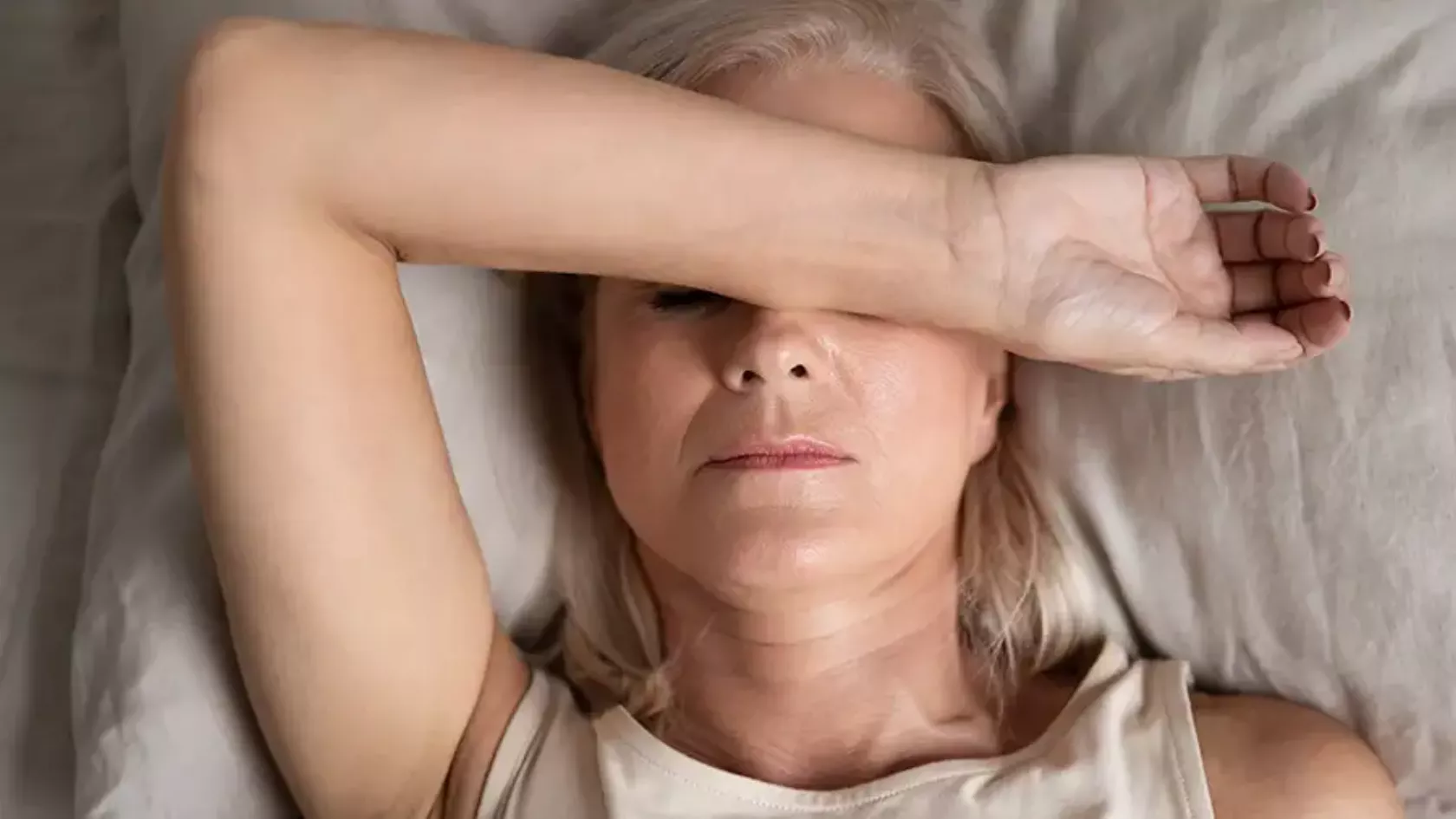 Menopausale Frau leidet unter einer Hitzewallung liegend im Bett.