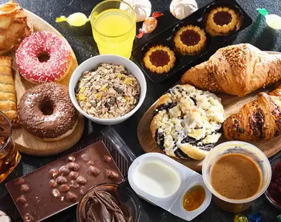 Auswahl an stark zuckerhaltigen Lebensmitteln wie Donuts, Gebäck, Limonade, Lutscher.