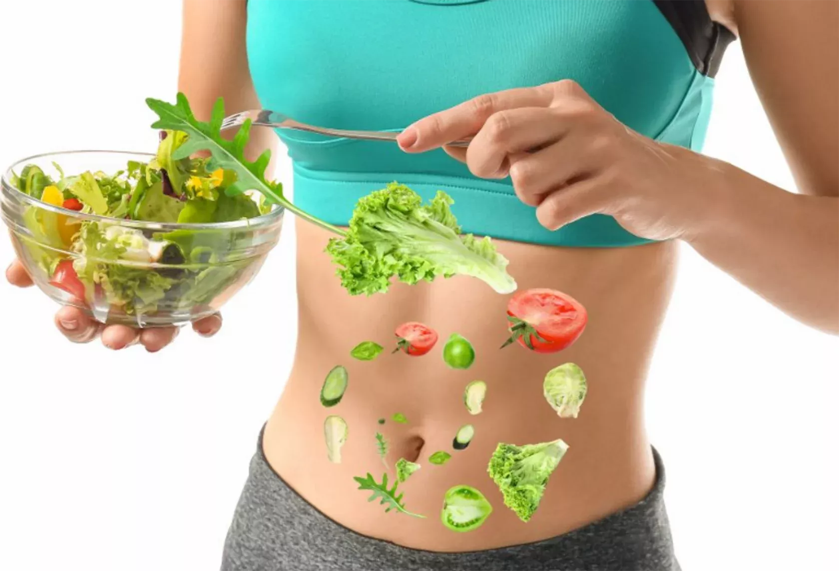 Schlanke Frau im Sport-Outfit hält eine Schüssel mit Salat vor ihren Bauch.