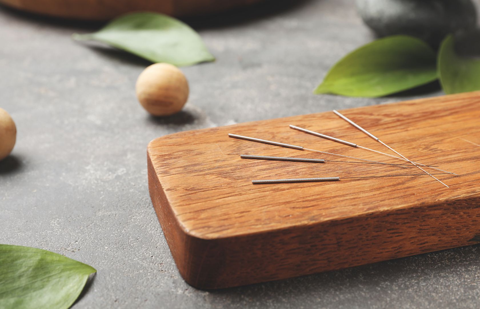 frische Akupunkturnadeln auf einem Holzbrett liegend