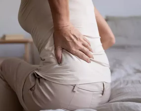 Seniorin fasst sich an den schmerzenden unteren Rücken - Lumbalgie.