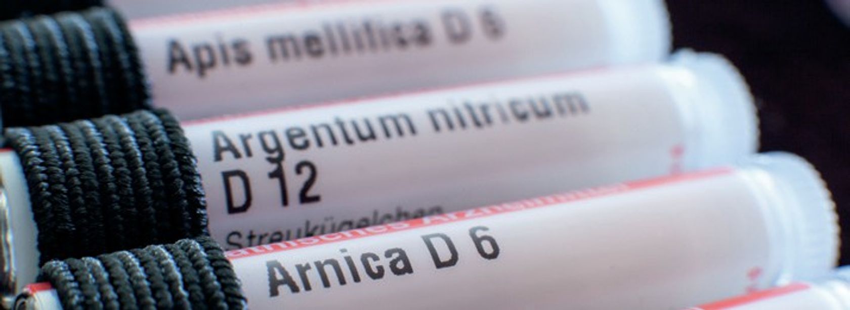 Behälter für Globuli sind zu sehen, die in einem Mäppchen stecken - Apis mellifica D6, Argentum nitricum D12, Arnica D6.