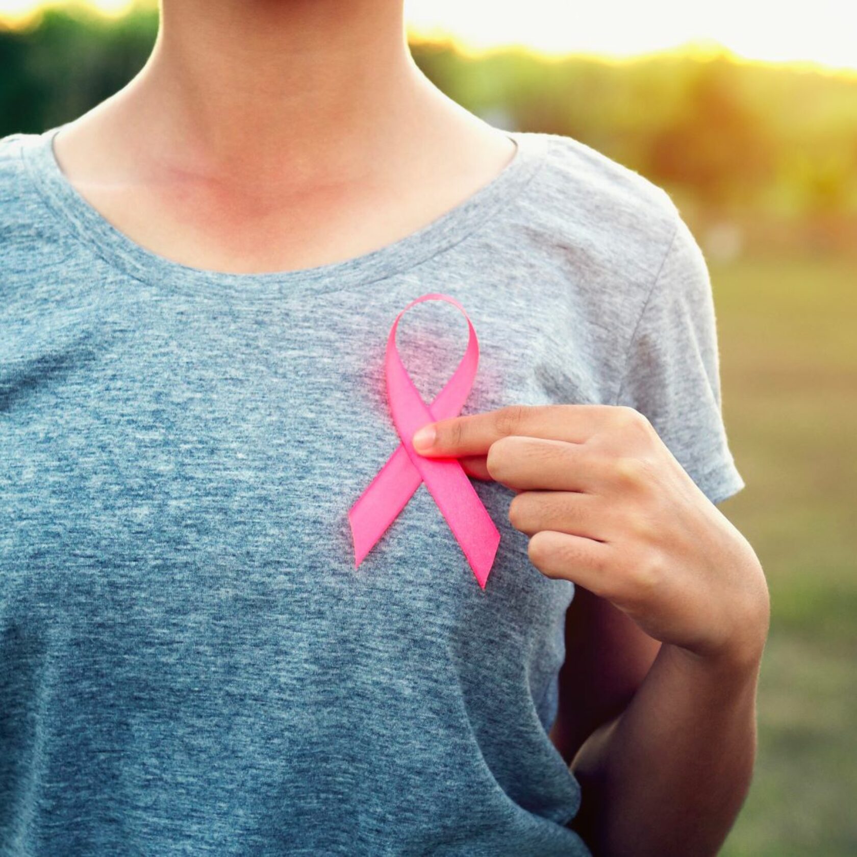weibliche Person hält sich eine Brustkrebs-Awareness-Schleife an die Brust