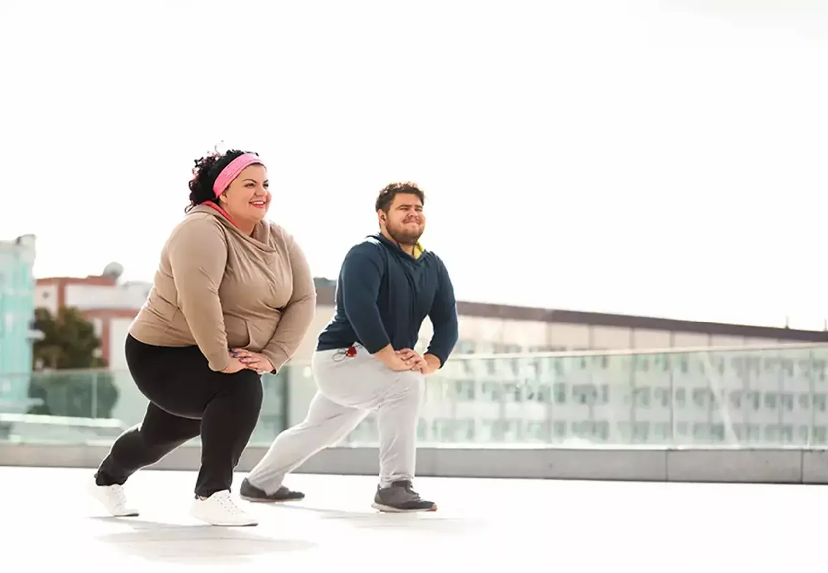Eine übergewichtige Frau und ein übergewichtiger Mann machen im Freien Stretching.